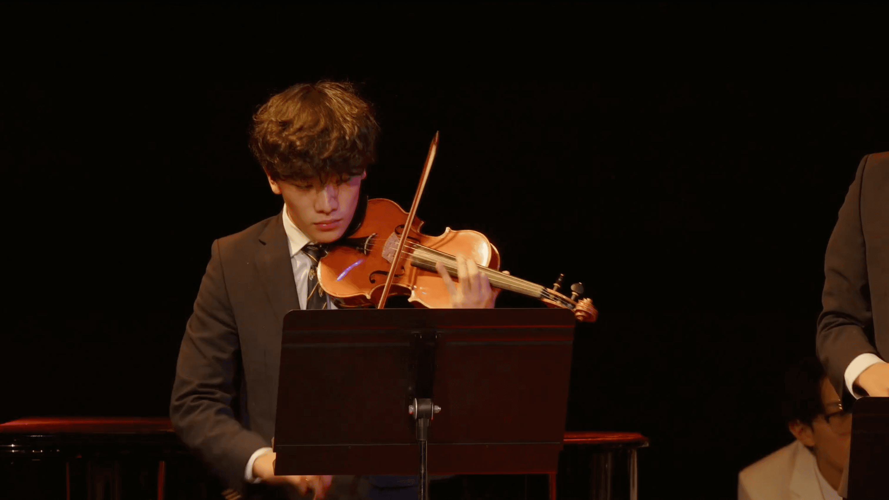 Alan playing violin on a dark stage